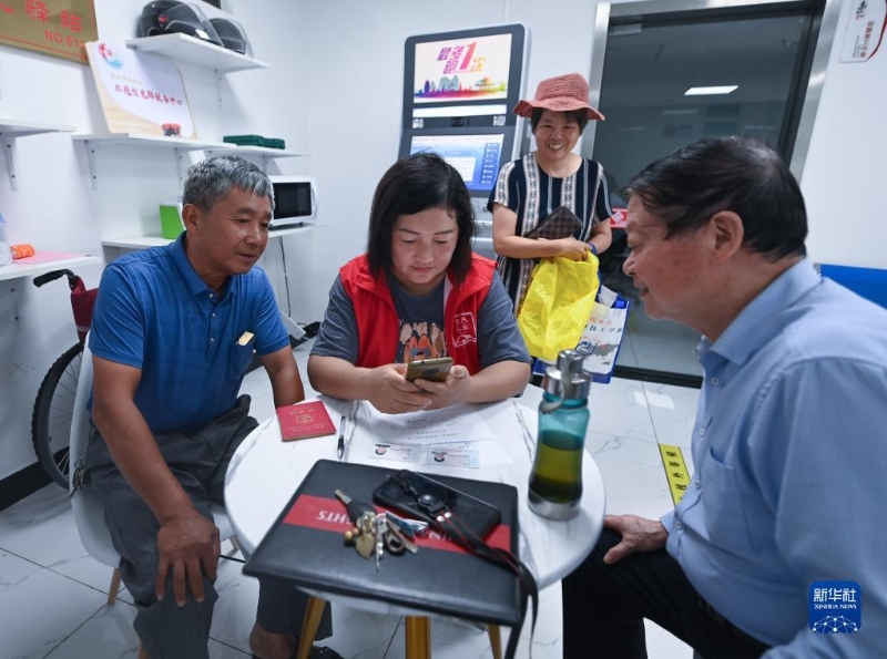 在浙江省杭州市臨安區(qū)玲瓏街道東山社區(qū)便民服務(wù)站，黨員志愿者幫助居民填寫公租房申請(qǐng)資料（2022年8月17日攝）。新華社記者 徐昱 攝