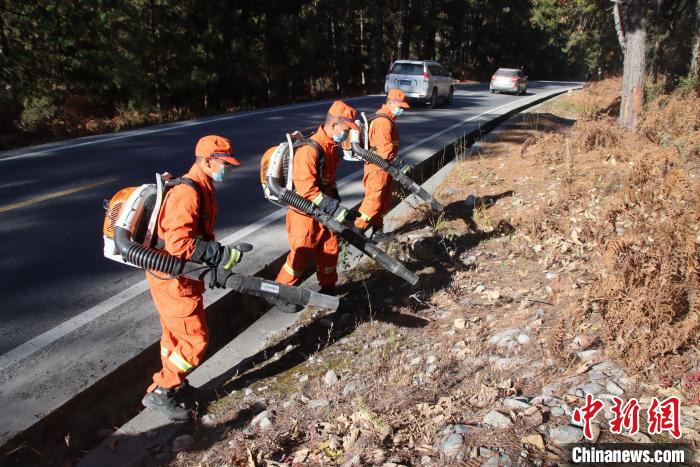 消防隊員利用風(fēng)力滅火機收攏國道旁可燃物?！⊥鯘蓷?攝