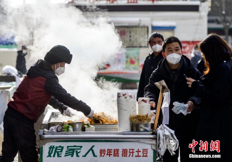 資料圖：外出購物的市民購買品嘗街頭小吃。 劉新 攝