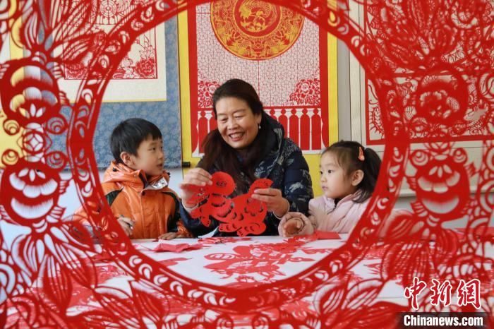 非遺傳承人田桂芹在帶領孩子們進行迎新年剪紙創(chuàng)作?！±詈?攝