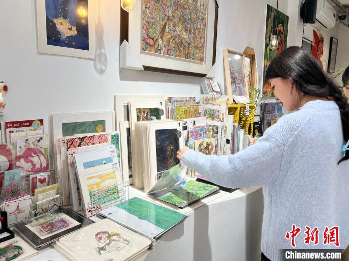 圖為藝術品商店內，顧客挑選插畫作品。　鐘旖 攝